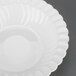 A close-up of a Fineline white plastic bowl with a scalloped edge.