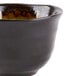 A black stoneware sake cup with brown and green accents.