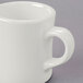 A close-up of a Tuxton eggshell white mug with a handle.