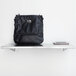 A Bobrick stainless steel wall mount shelf with a black purse on it.