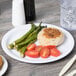A Carlisle white melamine plate with food including asparagus and tomatoes.