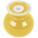 A yellow ceramic salt shaker with a white lid on a yellow surface.