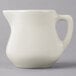 A white Tuxton China creamer pitcher with a handle.