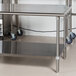 An Advance Tabco stainless steel work table with undershelf on wheels.