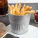 A galvanized metal bucket of french fries on a table.