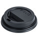 A Solo black plastic lid on a table over a coffee cup.