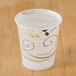 A Solo wax treated paper cold cup with a swirl design on a table.