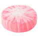 A round pink Lavex urinal cake covered in plastic wrap.