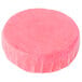 A pink round Lavex urinal cake with plastic wrap on a white background.