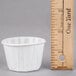 A white Solo paper souffle cup next to a ruler.