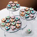 A Wilton three-tiered display stand with heart shaped cakes and cookies on it.