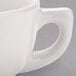 A close-up of a Tuxton eggshell white china cappuccino cup with a handle.
