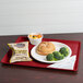 A Cambro cherry red dietary tray with a plate of broccoli and a drink.