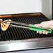A person using Vollrath Jacob's Pride tongs to cook on a grill.