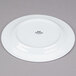 A Tuxton Alaska bright white china plate with a wide rolled edge and black text on it.