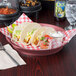 A plate of tacos on a table with a HS Inc. Raspberry Polypropylene Round Deli Server full of tacos.