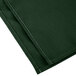 A close-up of a dark green Intedge cloth napkin with white stitching.