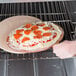 An American Metalcraft round pizza peel with a pizza being cooked in an oven.