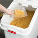 A hand pouring pasta into a white Rubbermaid ingredient storage bin.