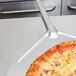 An American Metalcraft aluminum pizza peel with a pizza on it.