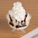 A Fineline Flairware clear plastic dessert cup filled with ice cream and chocolate syrup.