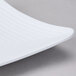 A close up of a white GET Milano square melamine plate with a curved edge.