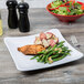 A Milano white melamine square plate with food including green beans and potatoes, a bowl of salad, and a fork.
