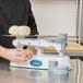 A person weighing dough on an Edlund stainless steel baker's dough scale.