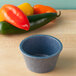 A blue HS Inc. polyethylene ramekin on a table next to a pile of red peppers.