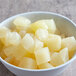 A white bowl of diced pears in light syrup.