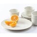 A Tuxton Venice ivory china plate with orange slices and cups on the side.