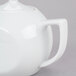 A close-up of a white CAC porcelain teapot with a lid and handle.