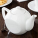 A CAC white porcelain teapot on a table.