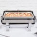 A Vollrath Orion electric chafing dish with shrimp and vegetables on a buffet table.