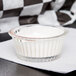A clear fluted plastic ramekin filled with white liquid.