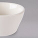 A Tuxton eggshell white china bowl with a small handle.