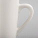 A close-up of a Tuxton Alpine white mug with a handle.