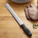 A Dexter-Russell V-Lo roast slicing knife cutting meat on a cutting board.