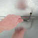 A hand using a metal tool to open a Norlake Kold Locker walk-in cooler.