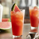 A Libbey tall mixing glass filled with watermelon juice and a slice of watermelon.