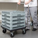 A person pushing a Vollrath Traex rack dolly with a stack of crates.