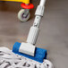A Unger gray jaw style mop holder with a blue sponge on a gray surface.