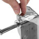 A hand using a screw to attach a metal rod to a Tellier countertop bread slicer.