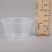 A clear Dart plastic souffle cup next to a ruler.