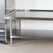 An Advance Tabco stainless steel equipment stand with a stainless steel undershelf.
