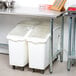 An Advance Tabco stainless steel work table with open base holding two white plastic containers.
