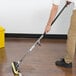 A person using a Rubbermaid cellulose sponge mop to clean a wood floor.