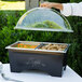 A person using a Sterno ChalkBoard Chafer with clear dome lids over a buffet.