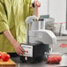 A man using a Robot Coupe food processor to dice tomatoes on a counter.