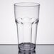 A close-up of a clear Carlisle plastic tumbler on a table.